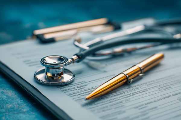 stethoscope and a pen on medical papers on a clipboard