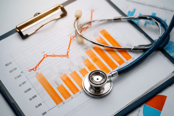 stethoscope lying on a clipboard with an orange bar chart and a line graph increasing