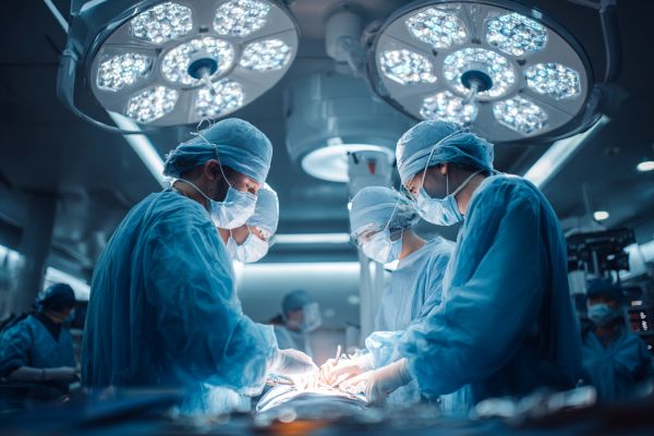 medical professionals operating on a patient in a brightly lit blue operating room