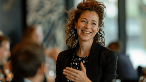 A businesswoman smiles while talking to seated coworkers in an office