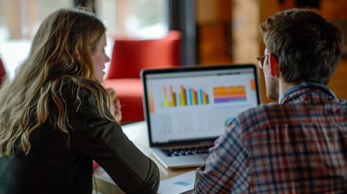 Two young professionals look at charts for reported information