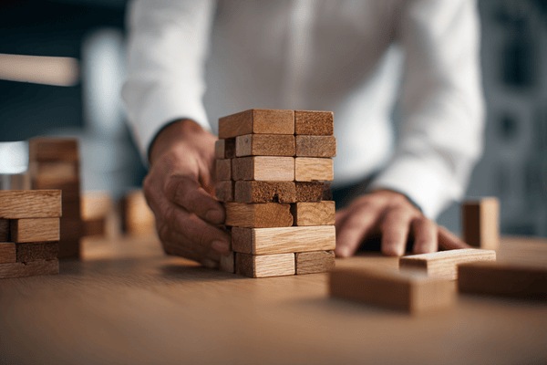 A buisinessman building a rectangular structure with wooden blocks that interlock
