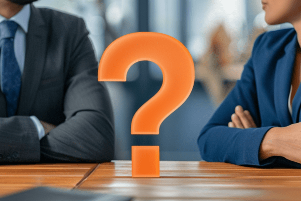 Businessman and adviser sitiing at a table with an orange question mark between them