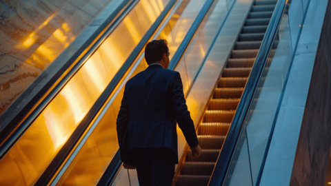 Businessman riding escalator to next floor
