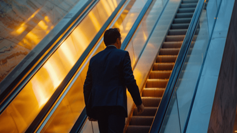 Businessman riding escalator to next floor