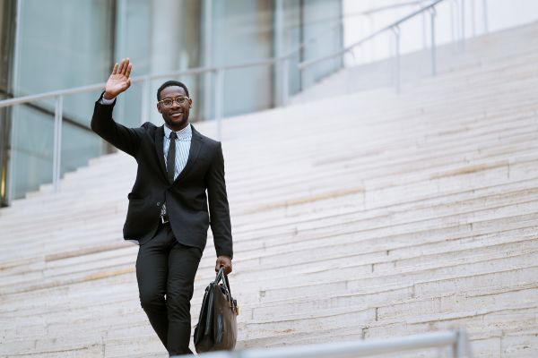 businessman carrying a briefcase walking down outdoor stairs waving