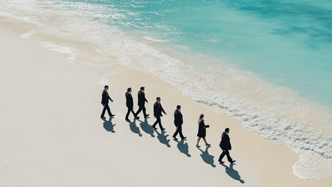 A group of businesspeople in suits walking on a beach in Bermuda