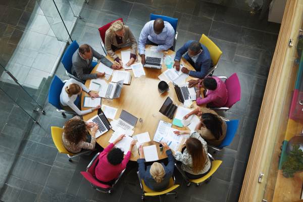 overhead view of businesspeople collaborating around a colorful round conference table