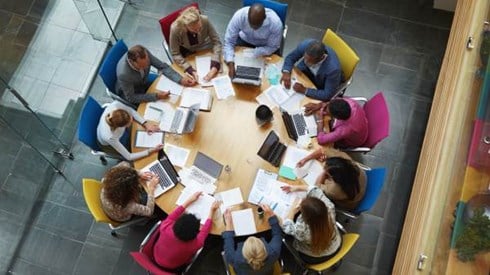 overhead view of businesspeople collaborating around a colorful round conference table