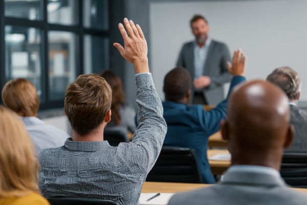 Businesspeople raising their hands in a class, watching an instructor