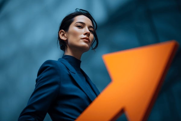 A businesswoman wearing a dark blue suit next to a bright orange arrow
