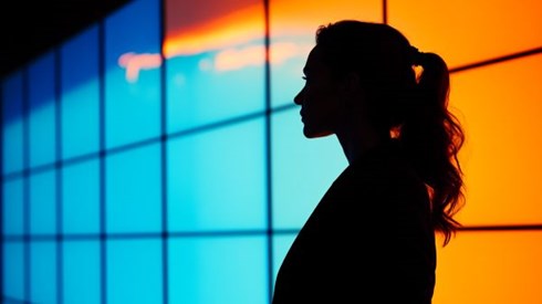 businesswoman silhouette in front of blue and orange screen