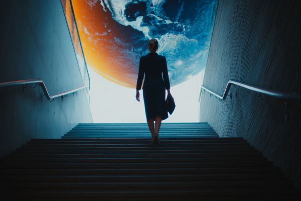 businesswoman carrying a briefcase walking up stairs towards a large globe