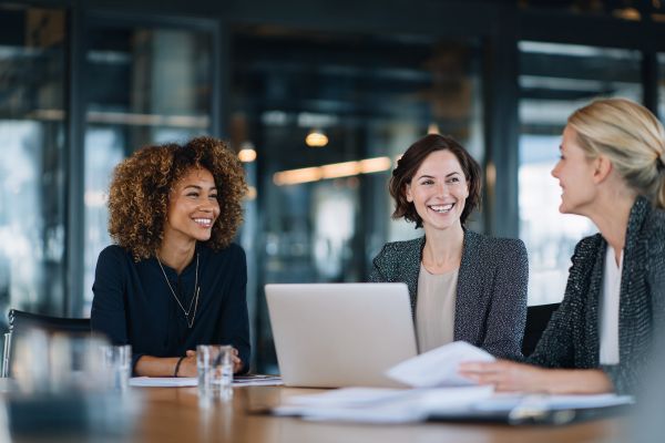 three happy businesswomen talking at a conference table