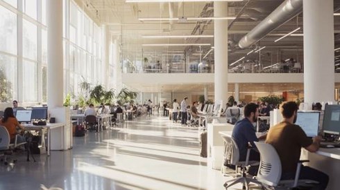 interior of bright sunny tech company office with casually dressed staff working at computer stations