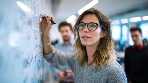 professor writing on a white board in front of students