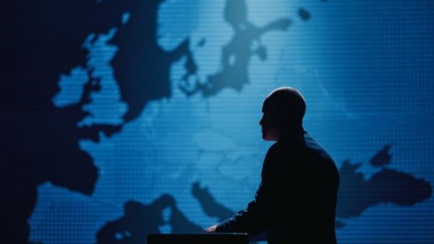 silhouette of a businessman standing at a podium in front of a blue map of Europe on the wall