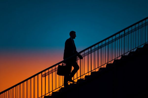 silhouette of a businessman holding a briefcase walking up stairs