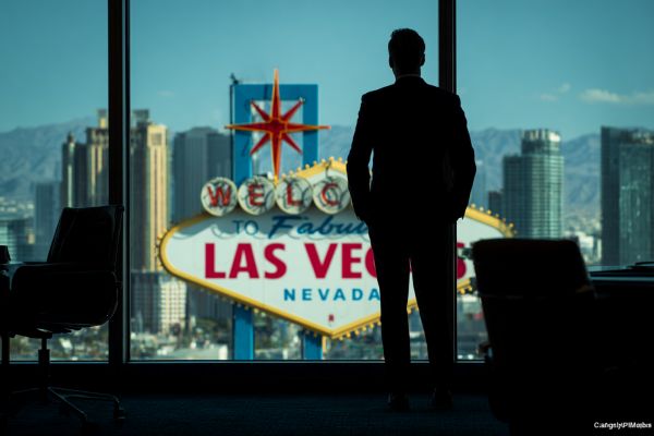 silhouette of a businessman in an executive office looking out a window overlooking the iconic Welcome to Las Vegas sign and the skyline