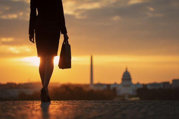 silhouette of a businesswoman holding a briefcase overlooking Washington DC at sunrise