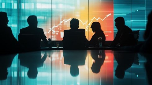silhouettes of businesspeople sitting at a table looking at charts on a screen