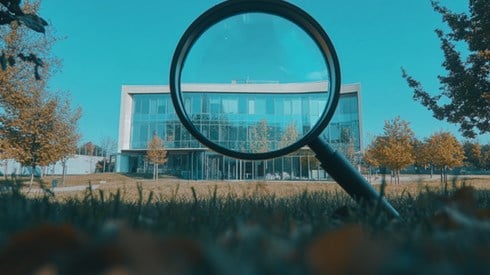 A magnifying glass examining a corporate building.