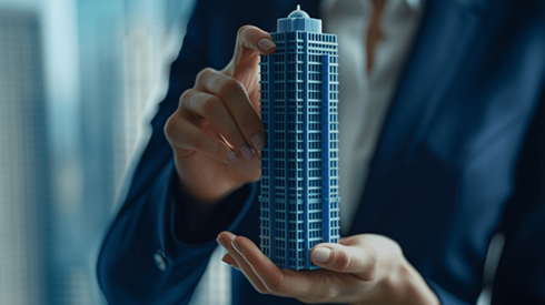 Businesswoman in a dark blue suit holding a model of a skyscraper
