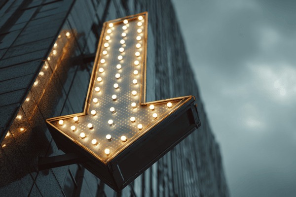 An arrow made out of lights pointing down on the side of a skyscraper
