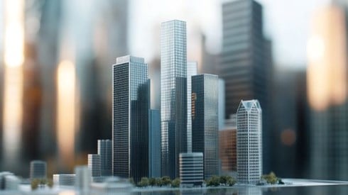 a scale model of commercial buildings in front of the real life versions of the same buildings