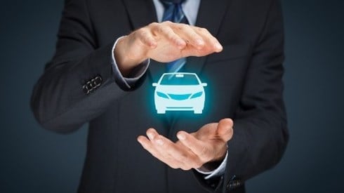 Businessman with his hands protecting a hologram of an auto