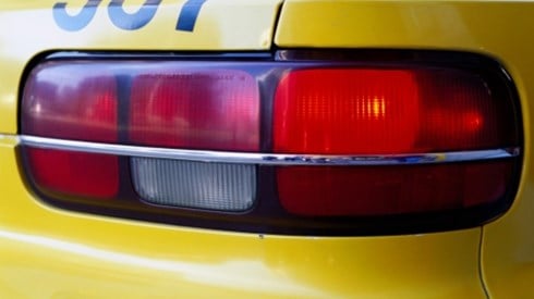 The right corner of the back of a yellow taxi cab showing red reflective brake lights and the number 337