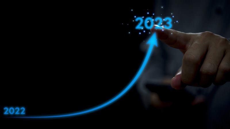 Hand with Index Finger Pointing at 2023 While Blue Upward Arrow Rises from 2022