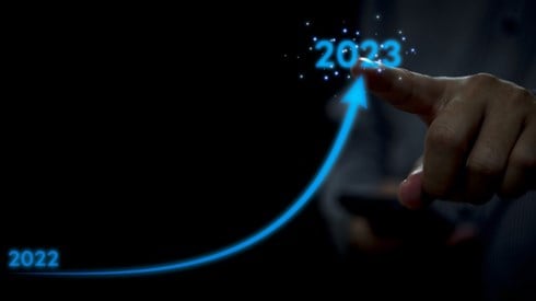 Hand with Index Finger Pointing at 2023 While Blue Upward Arrow Rises from 2022