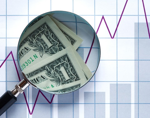 Dollar bills viewed through magnifier with graph in background