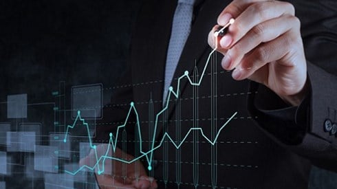 A man in a suit drawing a digital graph on glass with the line increasing