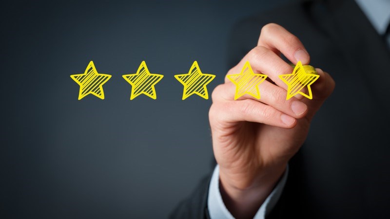 A businessman's hand drawing five yellow stars