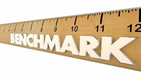 A tan 12-inch ruler with black inch markers and the word BENCHMARK in white letters stretching to the end on white background