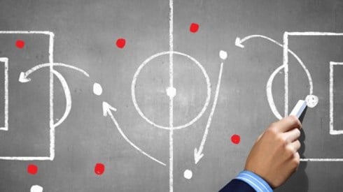 A businessman's hand drawing a game plan diagram in chalk