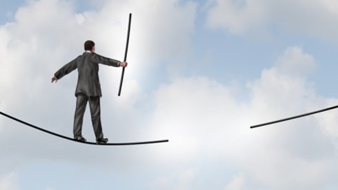 Businessman on a tightrope walking toward a missing piece in the middle of the tightrope with cloudy skies in the background