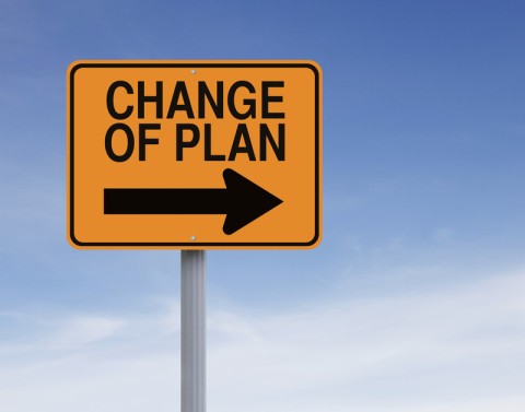 Yellow road sign with words CHANGE OF PLAN and an arrow pointing to the right