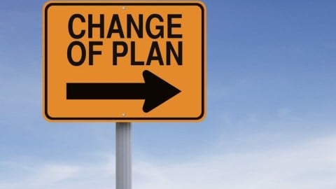 Yellow road sign with words CHANGE OF PLAN and an arrow pointing to the right