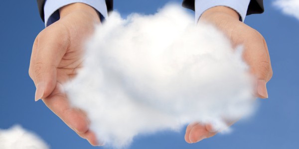 The hands of a business professional are in the sky and are holding a large puffy cloud