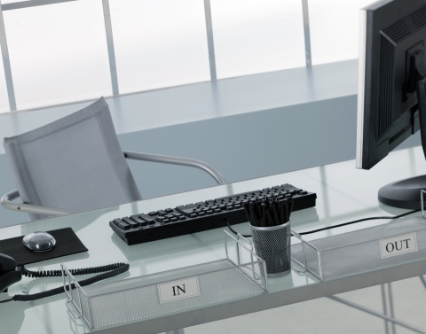 An empty modern style executive office with computer equipment and in and out boxes