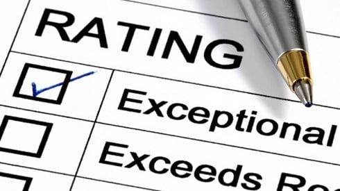 A pen rests on the top left corner of a Performance Review Rating sheet and the Exceptional rating is checked.
