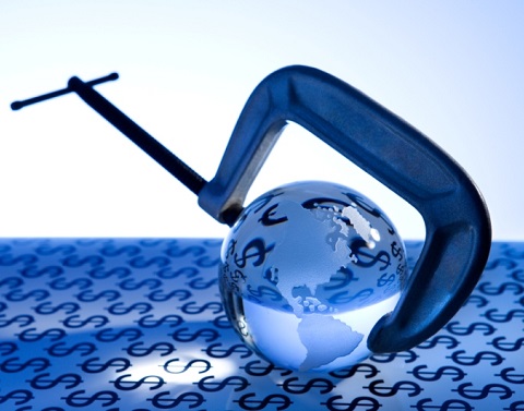 A glass globe reflecting the dollar signs from the table covering is in a G clamp vice.