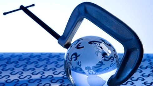 A glass globe reflecting the dollar signs from the table covering is in a G clamp vice.