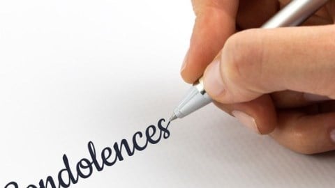 The word condolences being handwritten on a white piece of paper