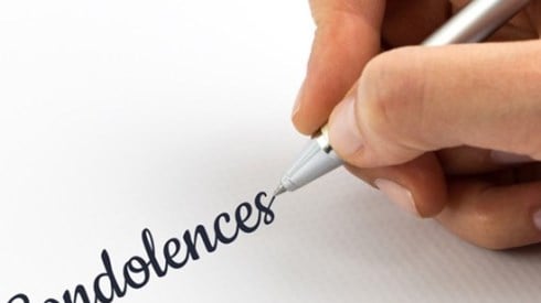 The word condolences being handwritten on a white piece of paper