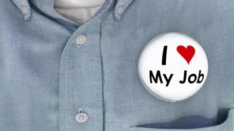 Closeup of a man´s shirt with a bubble pinback button that says I Love My Job with love symbolized by a red heart