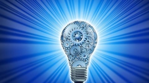 A light bulb filled with different sizes of gears emanates blue light